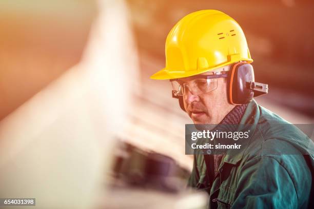 hombre que trabaja en el aserradero - orejeras fotografías e imágenes de stock