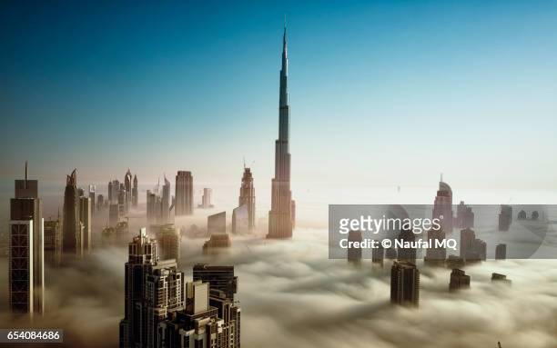 dubai skyline in early morning fog - burj khalifa stock-fotos und bilder
