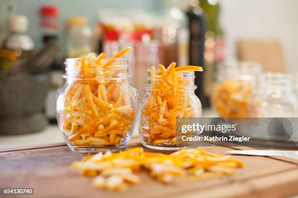 jars on kitchen counter filled with thinly cut orange zest - scorza di limone foto e immagini stock