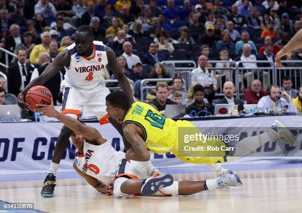Teammates Marial Shayok and Devon Hall of the Virginia Cavaliers battle for a loose ball against Denzel Ingram of the North Carolina-Wilmington...