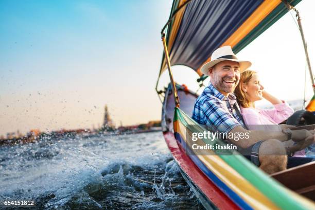 hombre de mediana edad y su compañera hermosa dama rubia en un paseo en barco en bangkok - couple traveler fotografías e imágenes de stock