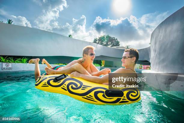 homosexual couple having fun in waterpark - ring swimming pool stock pictures, royalty-free photos & images