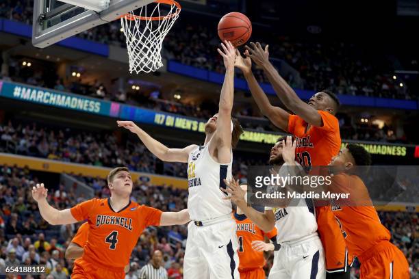 Nathan Adrian of the West Virginia Mountaineers and Nana Foulland of the Bucknell Bison fight for rebound during the first round of the 2017 NCAA...
