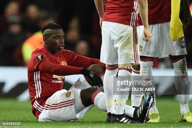 Manchester United's French midfielder Paul Pogba sits on the pitch injured during the UEFA Europa League round of 16 second-leg football match...
