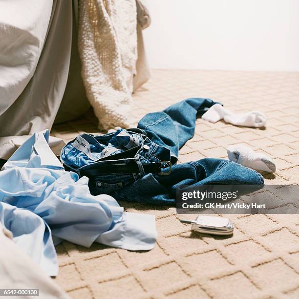 man's clothes on bedroom floor - jeans outfit photos et images de collection