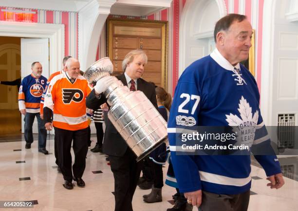 Phil Pritchard, curator of the Hockey Hall of Fame carries in the Stanley Cup with Hall of Famers Frank Mahovlich and Bernie Parent during the...