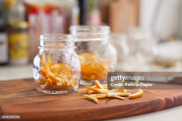 jars on wooden cutting board filled with thinly cut orange zest - zitruszeste stock-fotos und bilder
