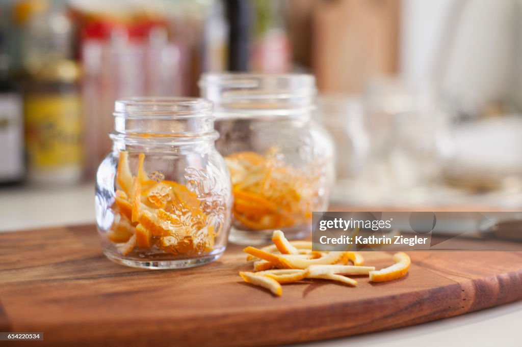 Jars on wooden cutting board filled with thinly cut orange zest