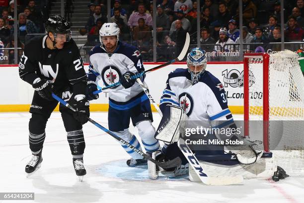 Connor Hellebuyck of the Winnipeg Jets makes a pad save in front of Anders Lee of the New York Islanders and teamate Paul Postma at the Barclays...