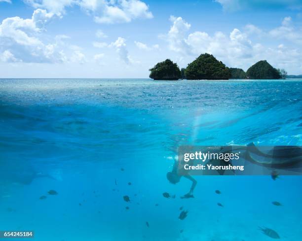 seascape with small island,people snorkeling under the water at palau - palau stock pictures, royalty-free photos & images