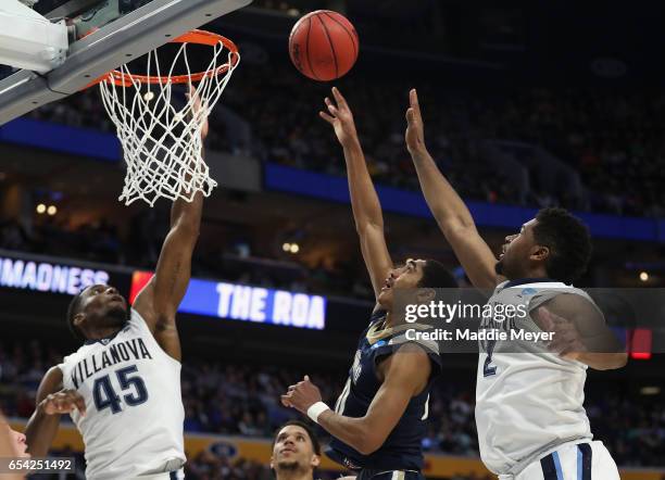 Miles Wilson of the Mount St. Mary's Mountaineers shoots against Darryl Reynolds and Kris Jenkins of the Villanova Wildcats in the second half during...