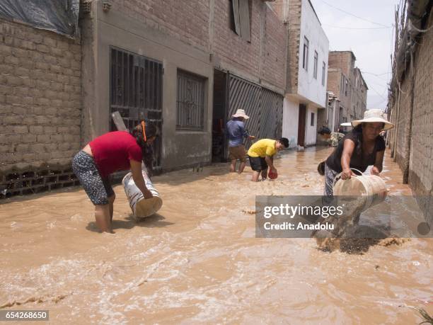 People use buckets to remove the mud and water left by a flood after Huaycoloro river overflowed in the area of Carapongo, a few kilometers from...