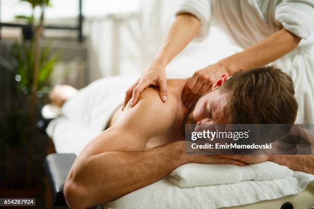 man having back massage at the health spa. - massajar imagens e fotografias de stock