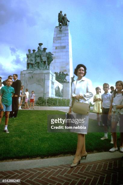 Low-angle view of future US First Lady Lady Bird Johnson as she poses in front of the This is the Place Monument, Salt Lake City, Utah, August 1963.