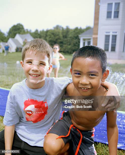 boys by water slide in garden - head bandage stock-fotos und bilder