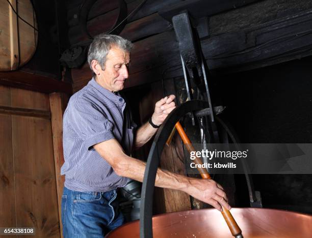 schweizer schafzüchter macht käse auf traditionelle weise in smokey schweizer berghütte - stirring stock-fotos und bilder