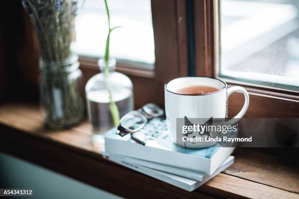 a cup of tea by a window - マグカップ ストックフォトと画像