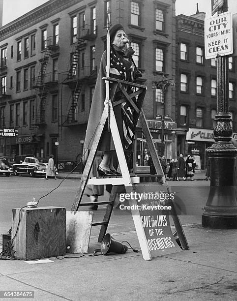 Woman, wrapped in the stars and stripes, standing on a ladder and using amplification equipment to campaign for clemency for the American couple...