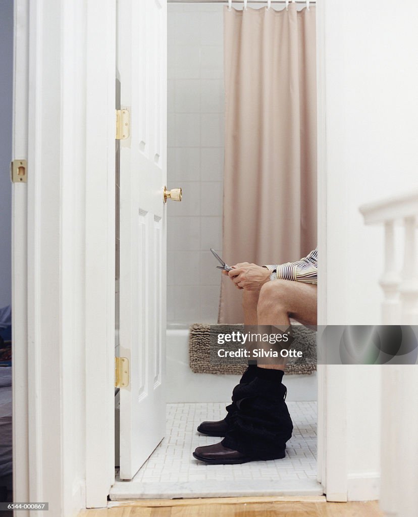 Man on Toilet Using Cell Phone