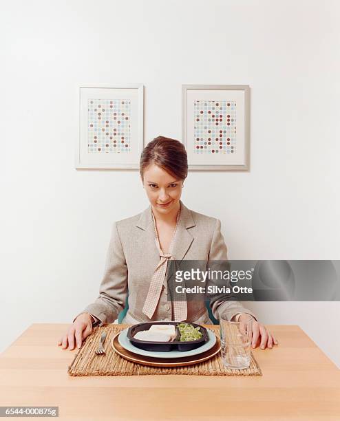 woman with convenience meal - sitting at table looking at camera stock-fotos und bilder