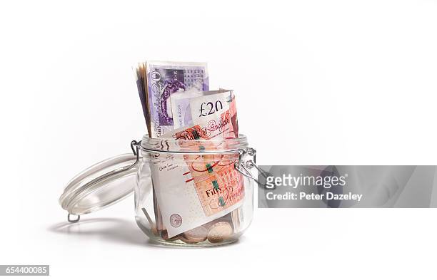 british pound notes in savings jar - livre sterling photos et images de collection