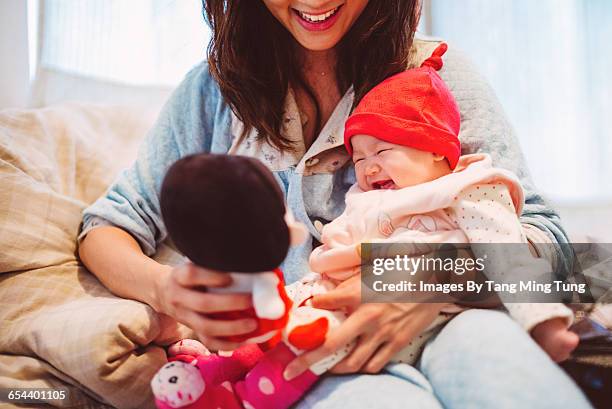 Young mom playing with baby joyfully on bed