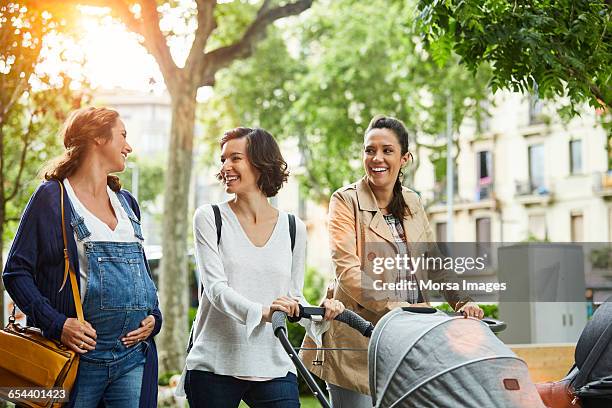 happy pregnant woman with friends in park - pregnant lady stockfoto's en -beelden