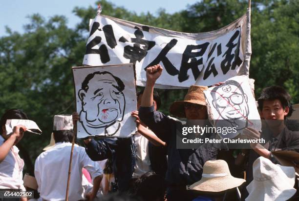 Pro-democracy demonstrators hold up protest banners and pictures against Chinese Premier Li Peng, as they watch thousands of other pro-democracy...