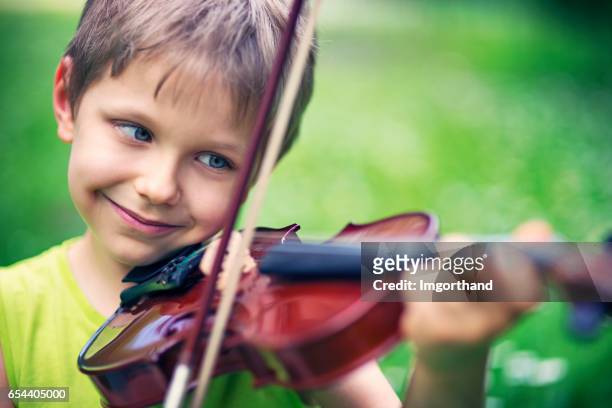 gelukkig jongetje viool spelen op grasveld voorjaar - boy violin stockfoto's en -beelden