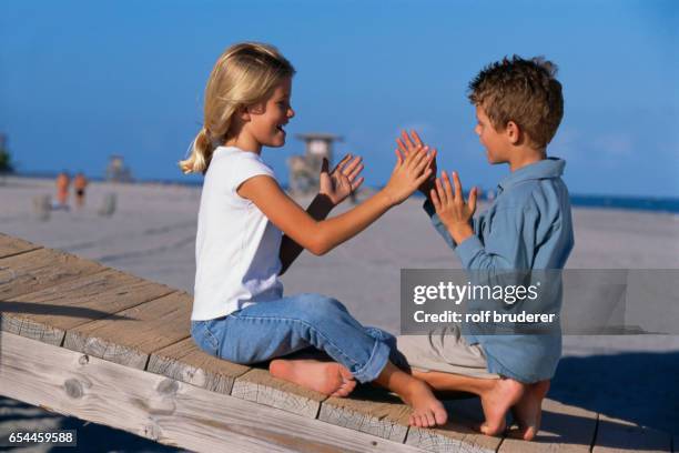 boy and girl playing hand game on beach - boardwalk game stock pictures, royalty-free photos & images