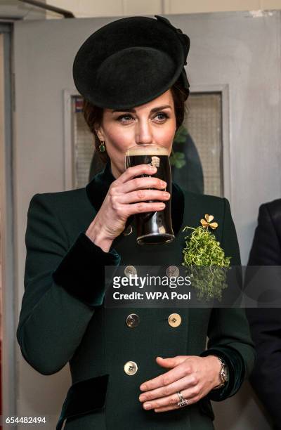 Catherine, Duchess of Cambridge takes a drink of Guinness as she meets with soldiers of the 1st battalion Irish Guards in their canteen following...
