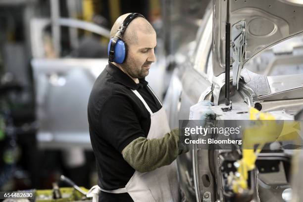 An employee works on a Jaguar XJ automobile in the body shop on the production line at Tata Motors Ltd.'s Jaguar assembly plant in Castle Bromwich,...