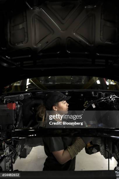 An employee works on a Jaguar XJ automobile in the final inspection area on the production line at Tata Motors Ltd.'s Jaguar assembly plant in Castle...