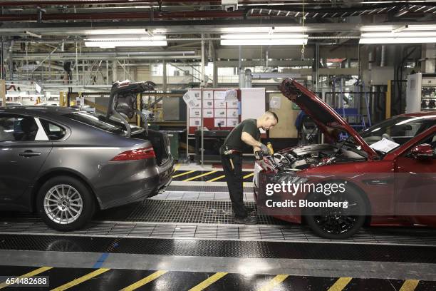 An employee works on the engine bay of a Jaguar automobile as it moves through the production line at Tata Motors Ltd.'s Jaguar assembly plant in...