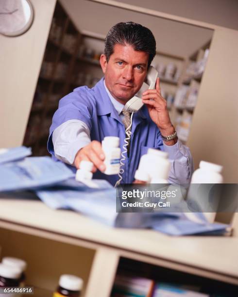 serious pharmacist talking on the phone - cali morales stock pictures, royalty-free photos & images