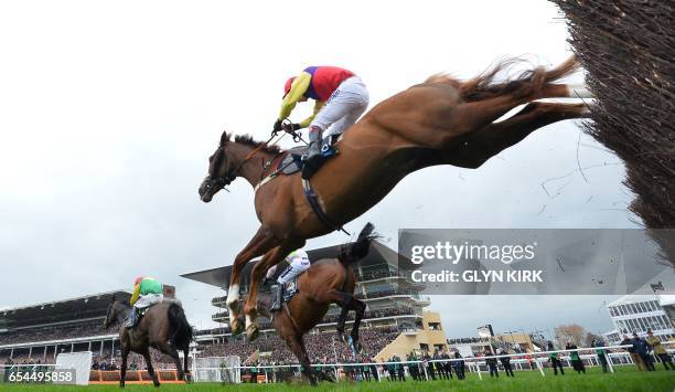 'Native River' ridden by jockey Richard Johnson jumps a hurdle behind eventual winner 'Sizing John' and Jockey Robbie Power during the Gold Cup race...