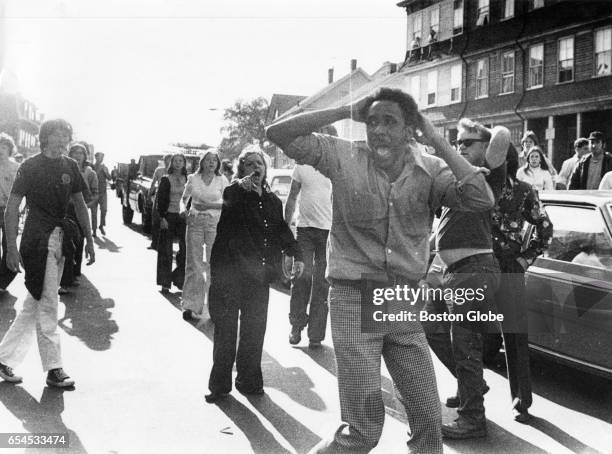 Jean-Louis Andre Yvon stands in the center of a street in South Boston, surrounded by a group of white men and women, on Oct. 7, 1974. Yvon was...