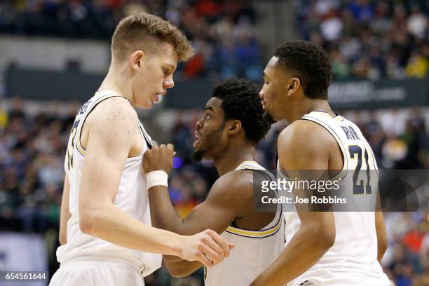 Derrick Walton Jr. #10 of the Michigan Wolverines talks with Moritz Wagner and Zak Irvin against the Oklahoma State Cowboys during the first round of...