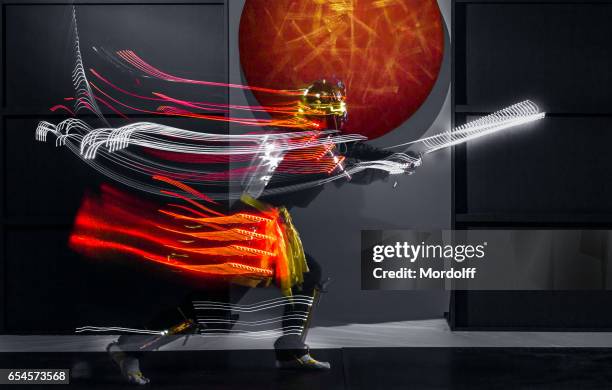 blurred motion of samurai in led clothing - swing sword stock pictures, royalty-free photos & images