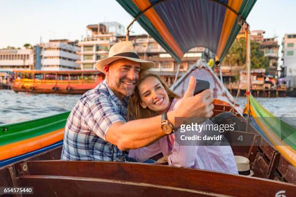 älteres paar unter selfies auf einen romantischen sonnenuntergang bootsfahrt kreuzfahrt auf dem fluss - schiffstaxi stock-fotos und bilder