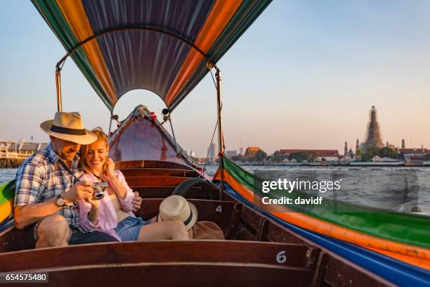 ouder paar op een romantische zonsondergang boot cruise op de rivier in bangkok thailand - longtailboot stockfoto's en -beelden