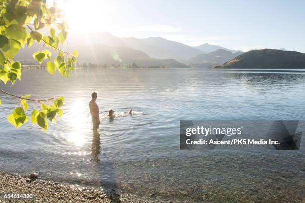 man watches woman float in mountain lake, sunrise - lake sunrise stock pictures, royalty-free photos & images