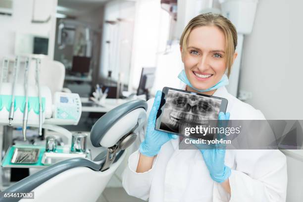 attractive dentist showing dental x-ray on touchpad - dental record stock pictures, royalty-free photos & images