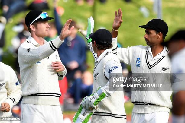 New Zealand's James Neesham celebrates taking the catch of South Africa's Stephen Cook with teammates Jeet Raval and BJ Watling during day three of...