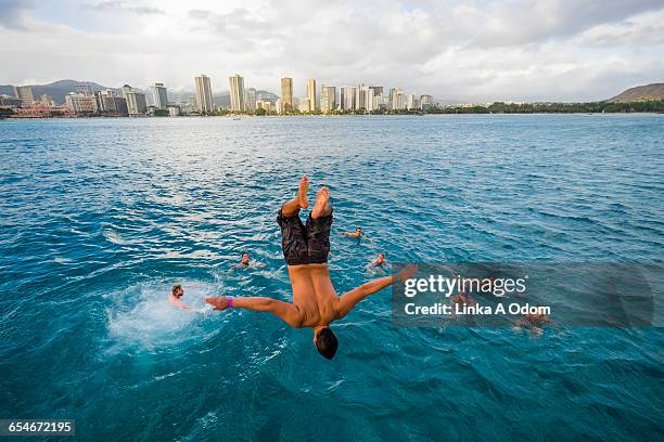 adult male backflipping into ocean - honolulu stock pictures, royalty-free photos & images