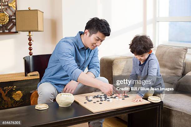 little boy playing the game of go with father - asian games day 2 stock-fotos und bilder