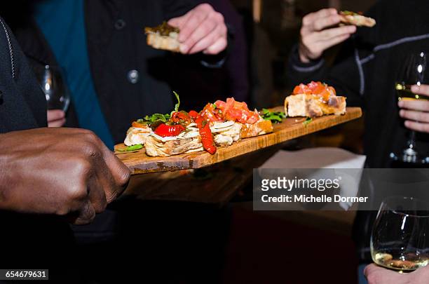waiter holding wooden platter of finger foods, serving it to guests, johannesburg, gauteng, south africa. - wine glass finger food stock-fotos und bilder