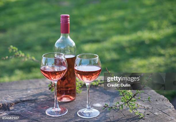 two wine glasses and bottle of rose wine on wooden table - vino rosado fotografías e imágenes de stock