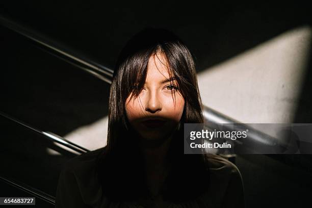 portrait of a woman's face in shadow - schlagschatten stock-fotos und bilder