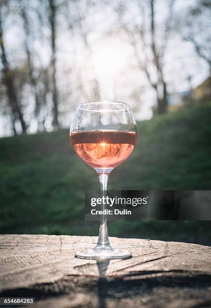 glass of rose wine on wooden table - single rose stockfoto's en -beelden